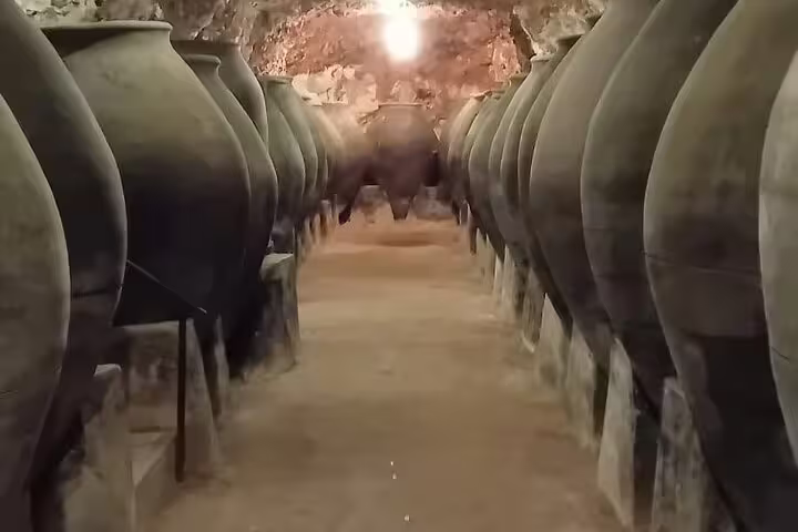 Ancient wine storage room with large clay amphorae lined up in a historic Madrid winery cellar.