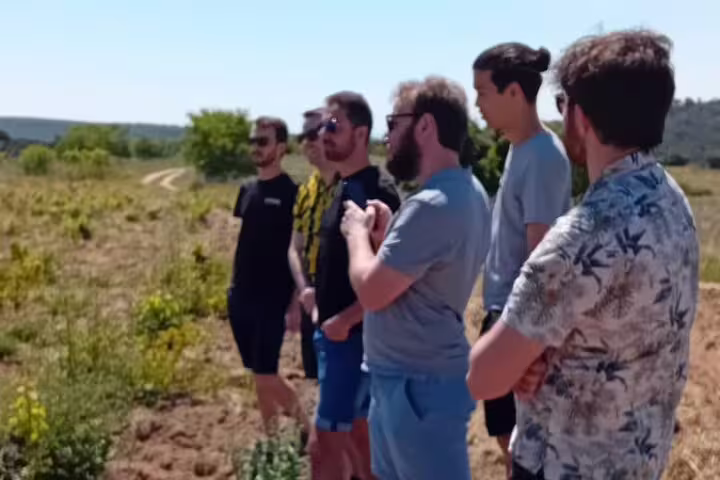 Group of tourists exploring Madrid's scenic vineyard landscape during a guided winery tour experience.