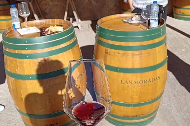 Wooden barrels set up for outdoor wine tasting at Madrid winery, featuring a glass of red wine in the foreground.