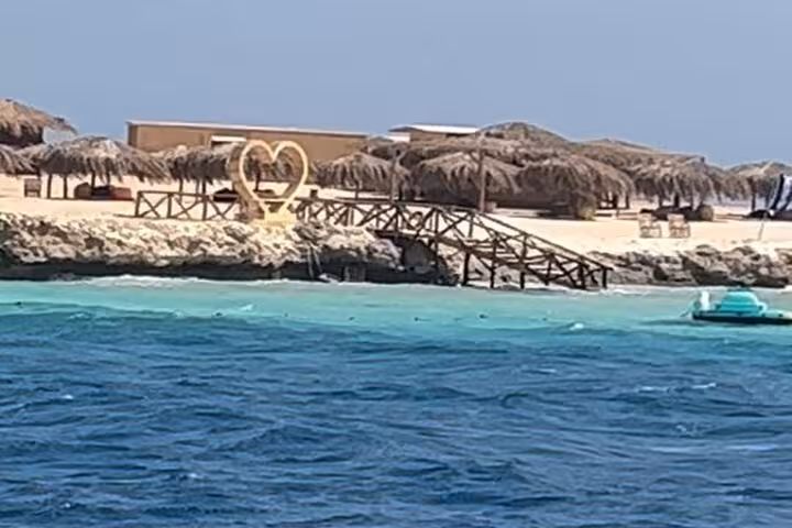 Magawish Island beach from the sea with wooden pier and huts on a private speedboat snorkeling trip Hurghada