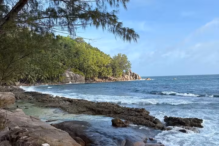 Picturesque rocky coastline with turquoise waters and lush greenery on Mahe island, Seychelles.