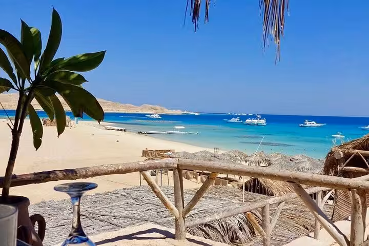 Mahmya Island beach view from hut terrace, turquoise Red Sea and boats on private speedboat tour