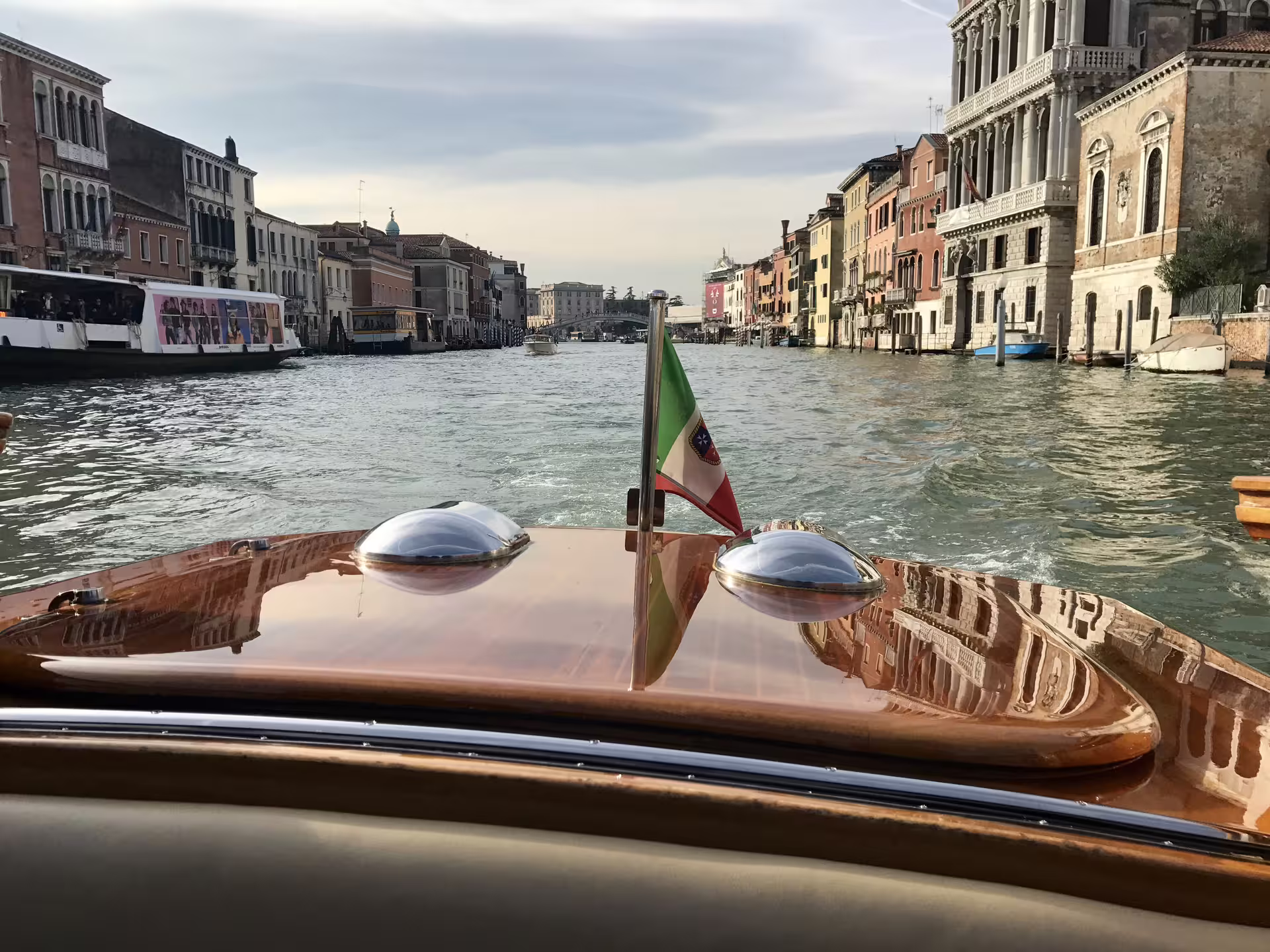 View from a mahogany boat cruising through Venice's iconic Grand Canal, highlighting historic architecture.