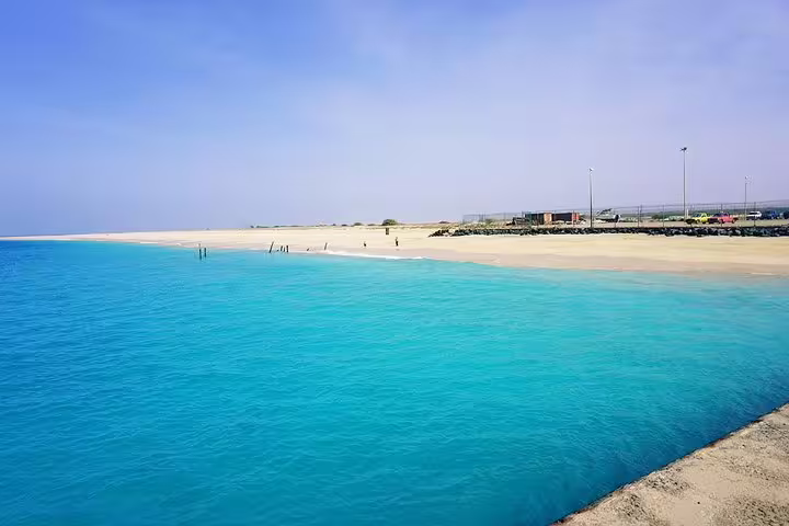 Stunning view of Maio Island's pristine sandy beach with crystal-clear turquoise waters under a vast blue sky.