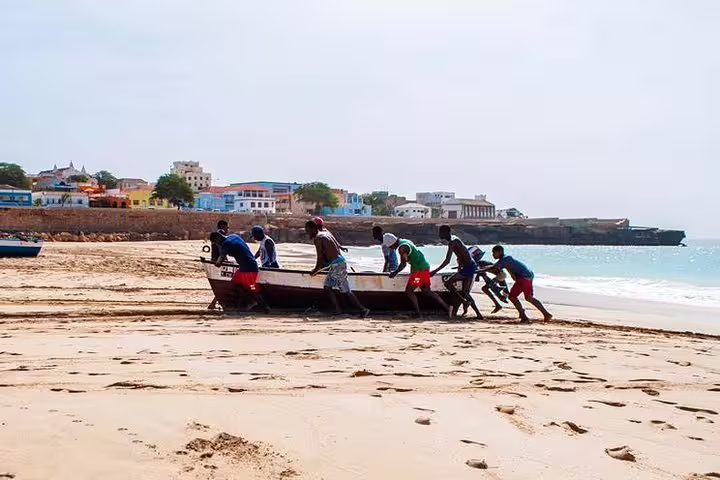 Local crew pushing a fishing boat on Maio Island shore, Cape Verde, during guided island tour with lunch