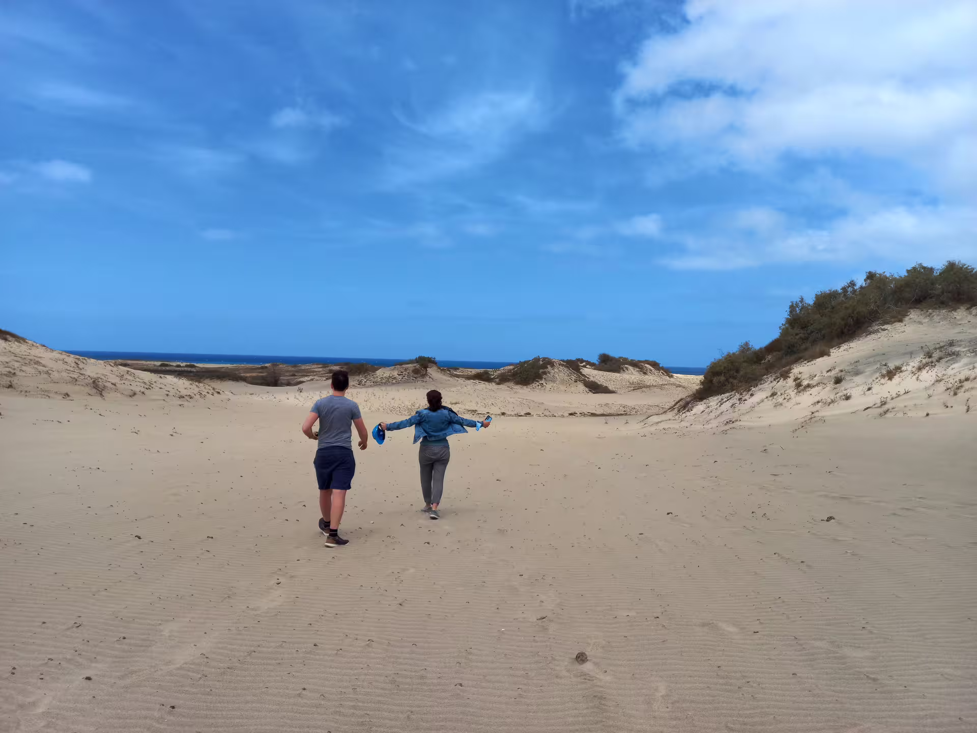 Couple enjoying a scenic walk on the serene sand dunes during a Maio Island tour from Praia.