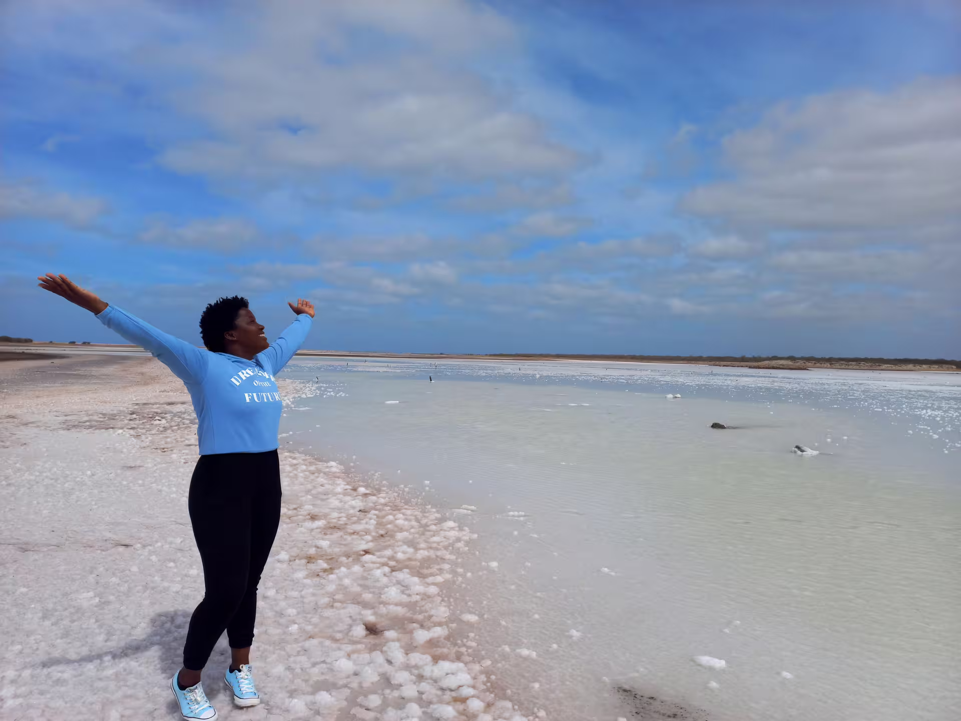 A joyful person with outstretched arms enjoying the serene salt flats on a Maio Island tour.
