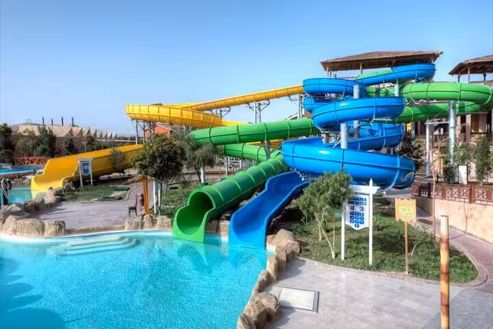 Blue and green tube slides splashing into pool at Makadi Water World aqua park from Hurghada Makadi Safaga