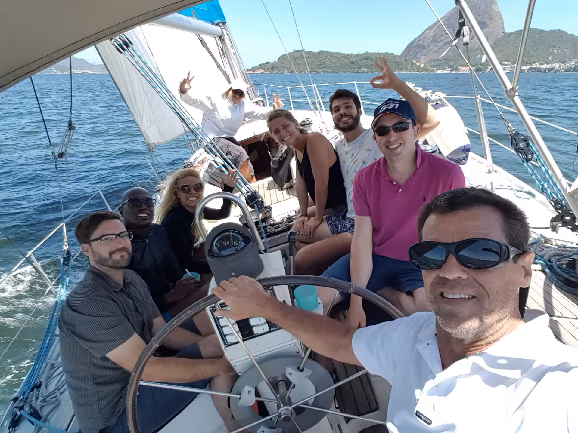 Happy group of people posing on the deck of a sailboat during a fun Makani Maikai private sailing adventure.