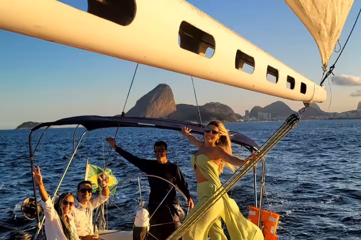 Group celebrating on the MAKANI MAIKAI sailboat at sunset with stunning views of Rio's iconic skyline.