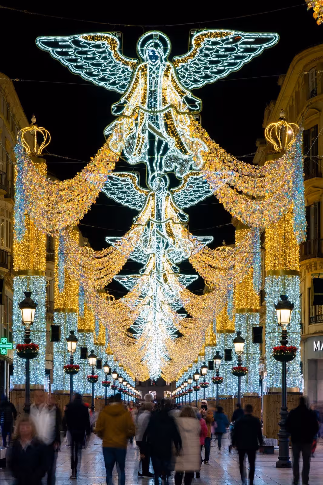 Vibrant angel-themed Christmas lights display adorns Malaga street, attracting crowds during the festive season.