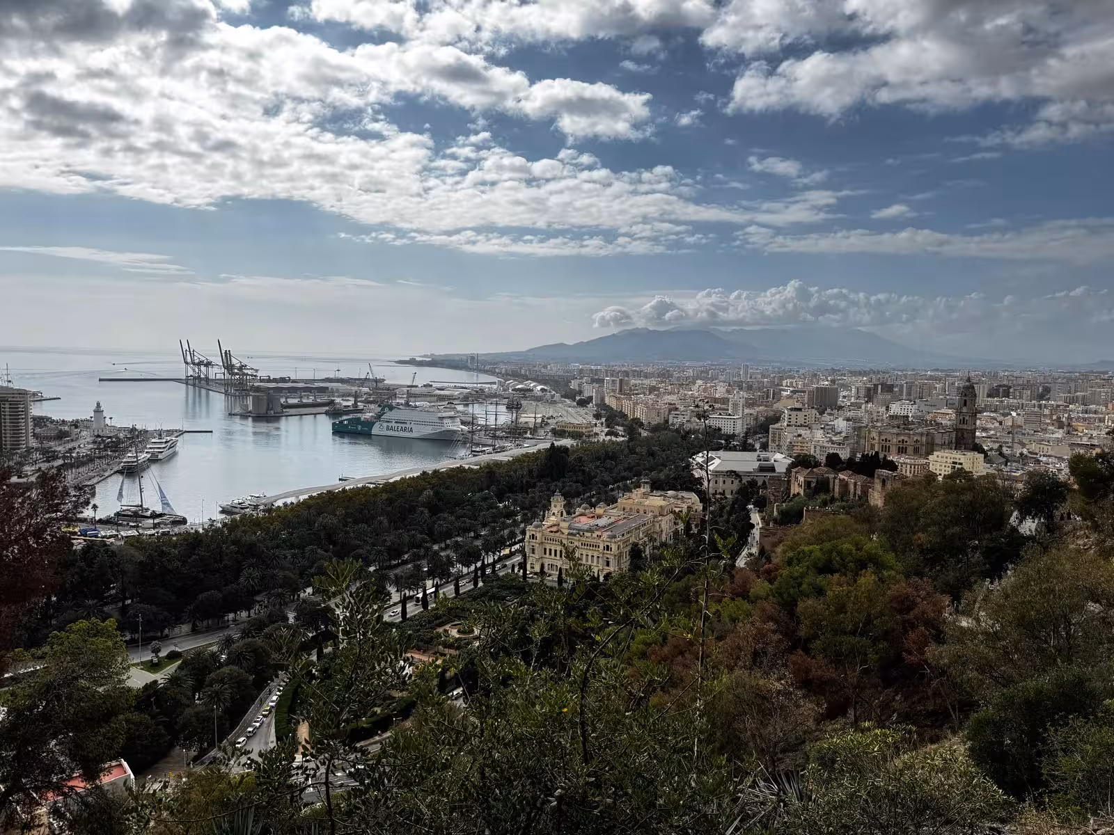 Panoramic view of Málaga’s coastline, harbor and city under a cloudy sky