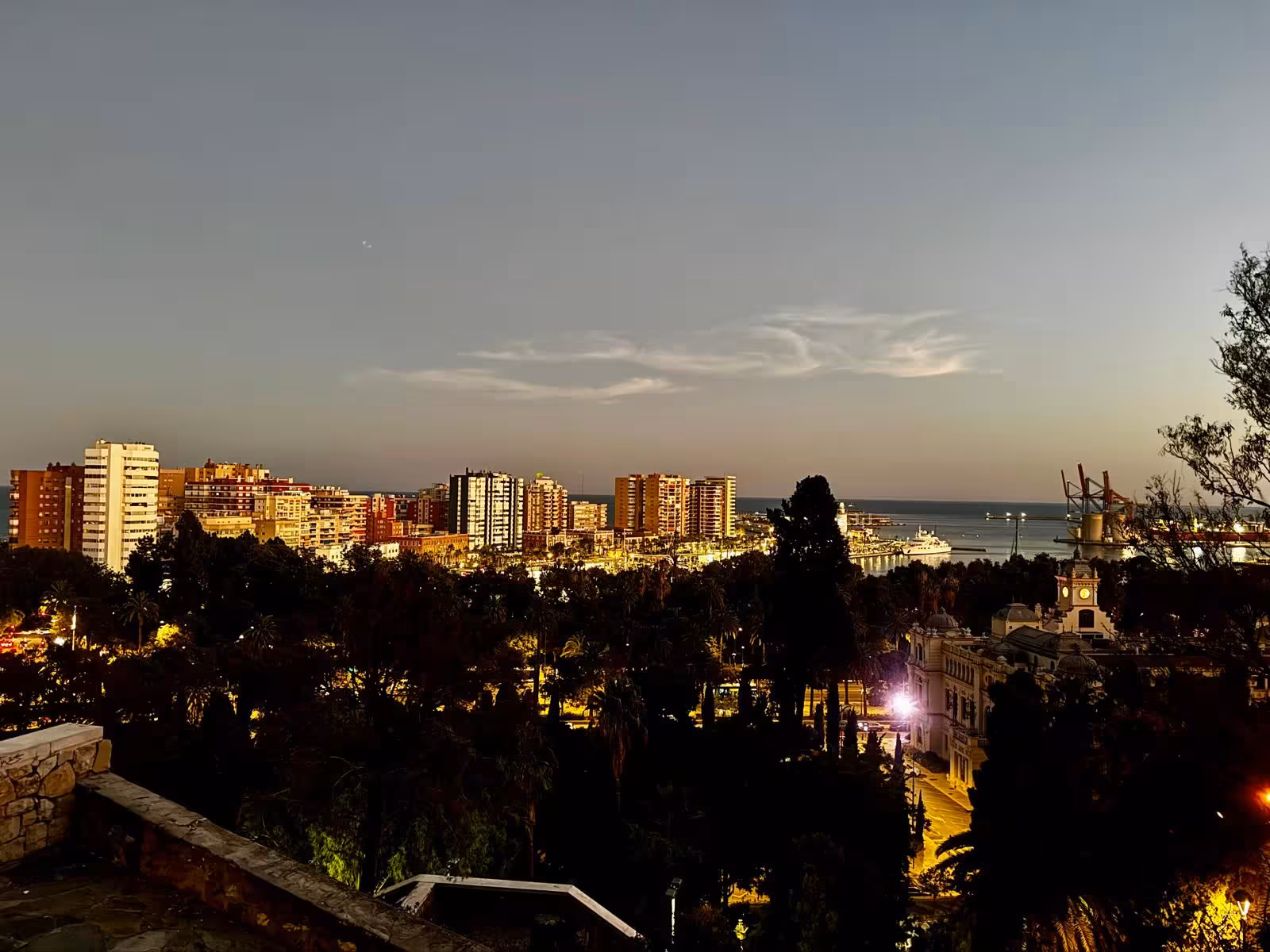 Evening cityscape of Málaga with illuminated buildings at dusk.