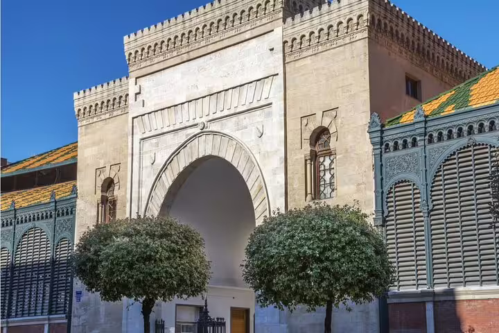 Moorish arch entrance of a historic building in Malaga city center with ornate stone carvings and green ironwork