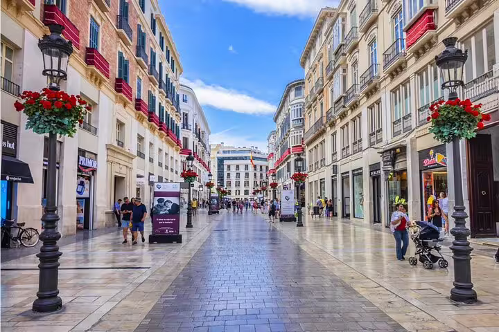 Pedestrian shopping street in Malaga historic city center with ornate lamp posts and red flower baskets