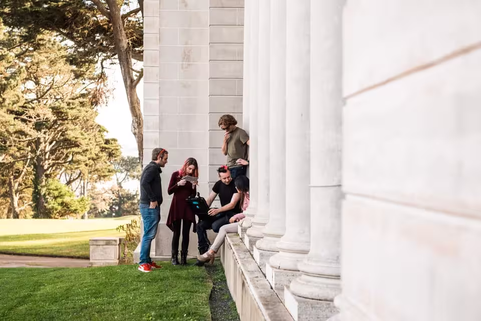 Group of people strategizing for Malaga outdoor escape game near grand columns.