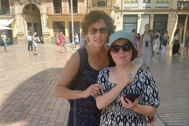 Travelers using a phone in Malaga plaza on a self-guided scavenger hunt and sights tour of historic center