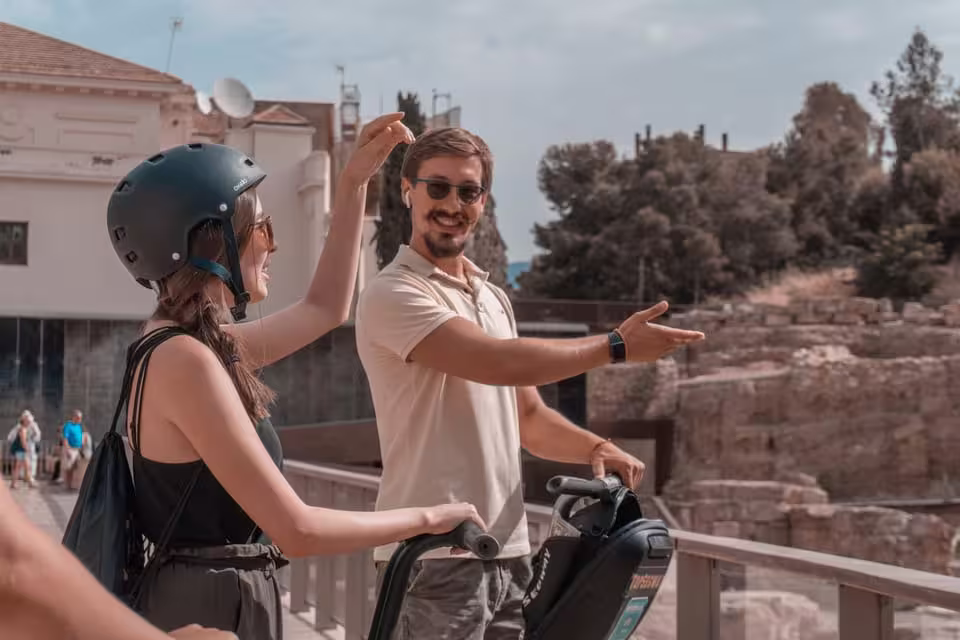Tour guide explaining ancient ruins during a Segway tour stop in Malaga with engaged participant.