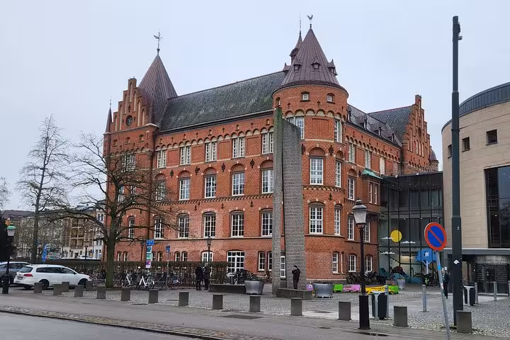 Majestic red brick building with Gothic architecture in Malmö, showcasing historical charm and vibrant city life.