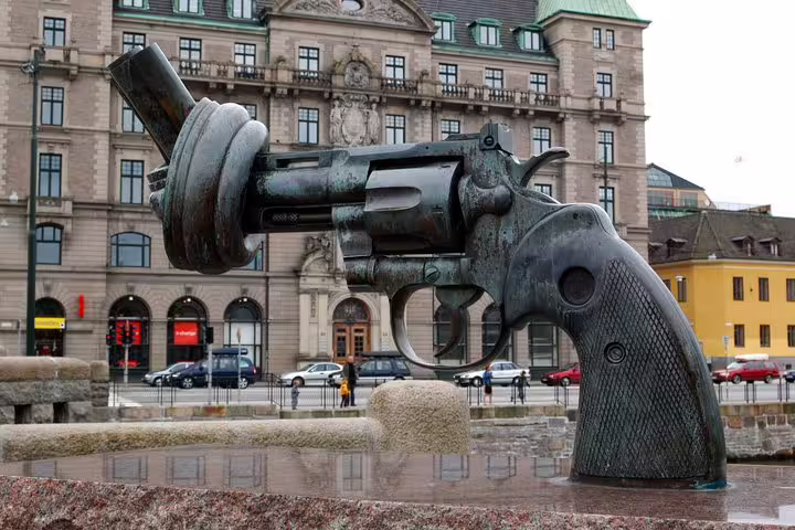 Sculpture of a knotted gun in Malmö, symbolizing peace, located near historic buildings on a private full day trip from Copenhagen.
