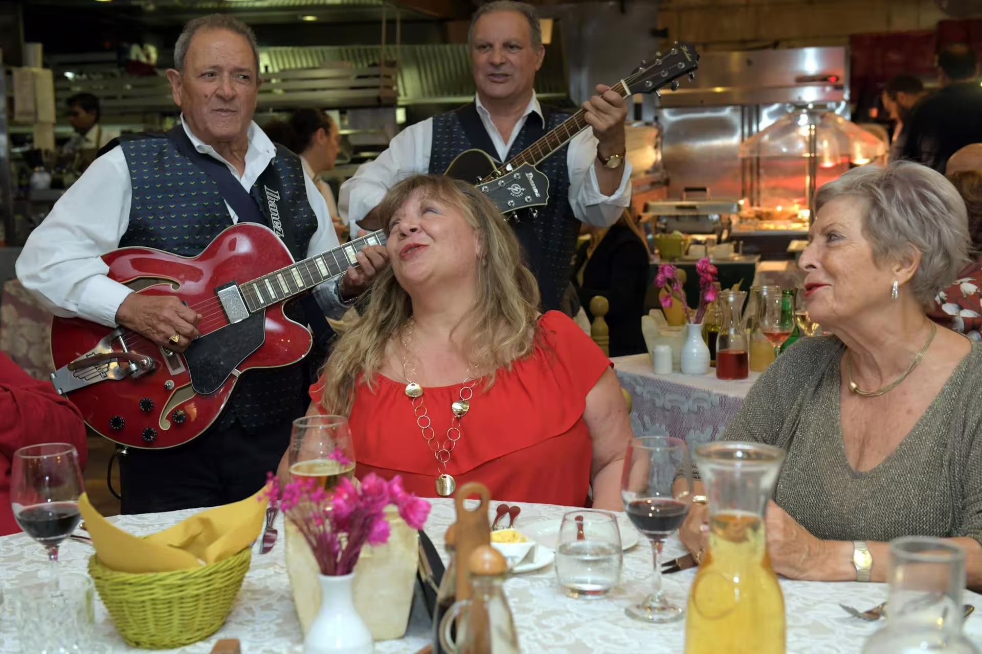 Musicians play guitars for guests enjoying traditional Maltese cuisine at a lively folklore night tour dinner.