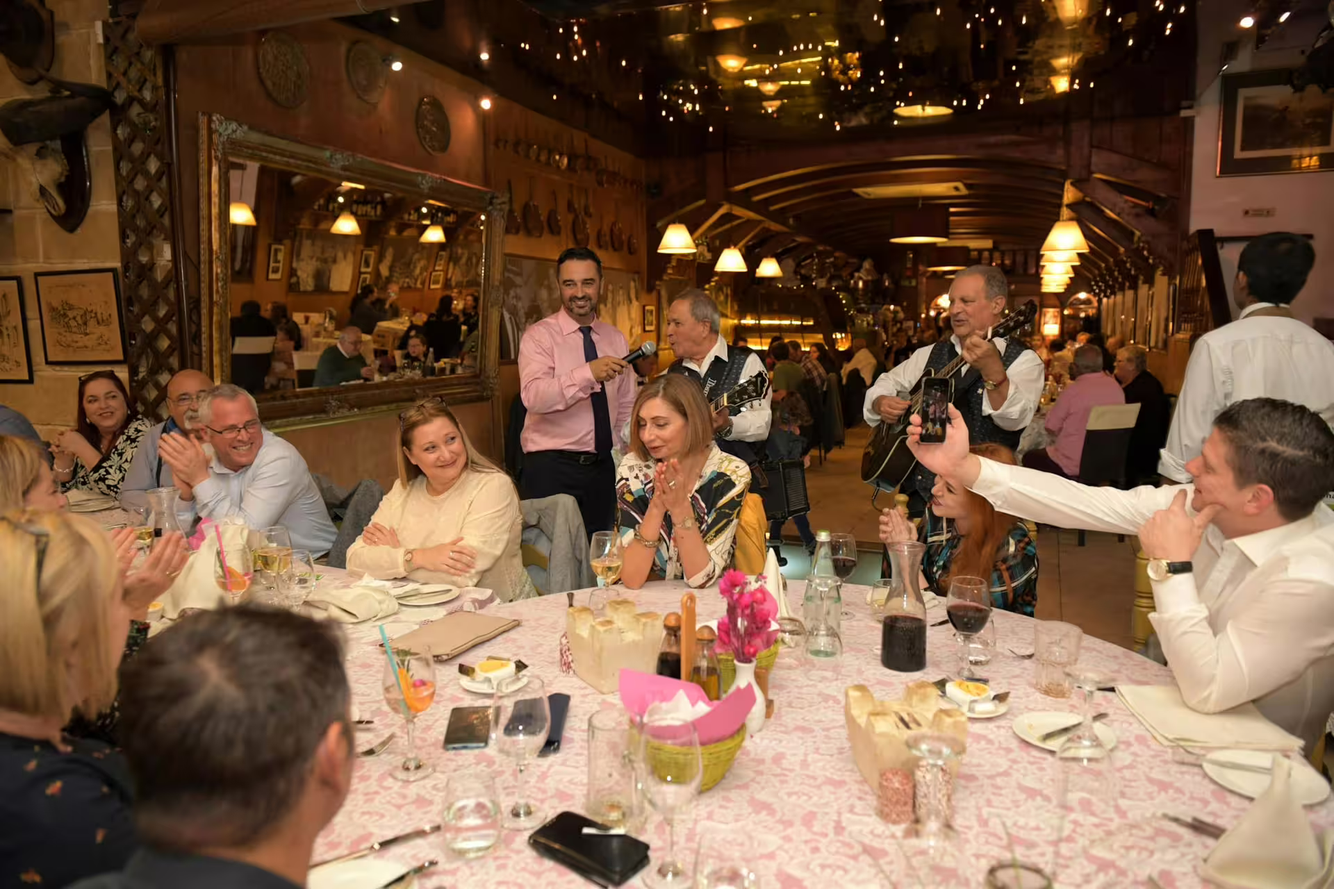 Guests clap and take photos as musicians perform at a Maltese folklore night tour, creating a lively atmosphere.