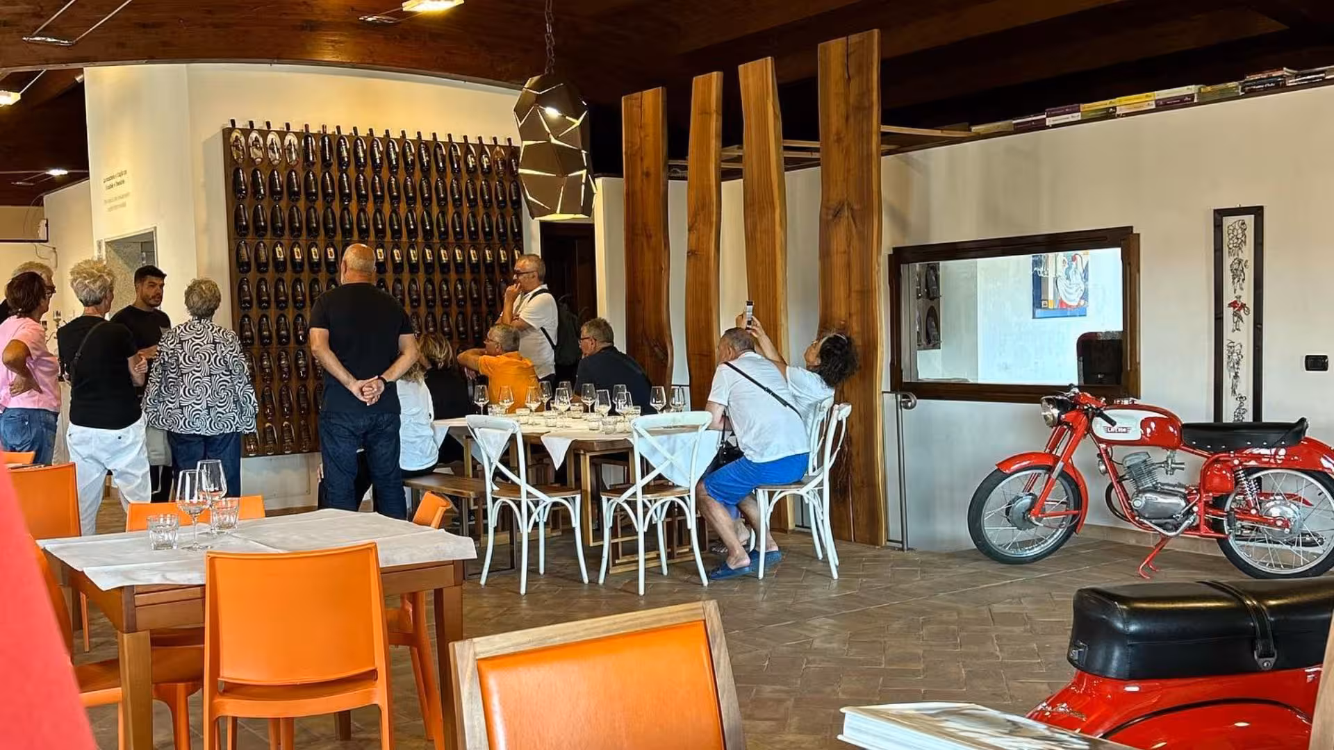 Visitors enjoy a wine tasting experience in Mamoiada's stylish tasting room, surrounded by local decor and vintage bikes.