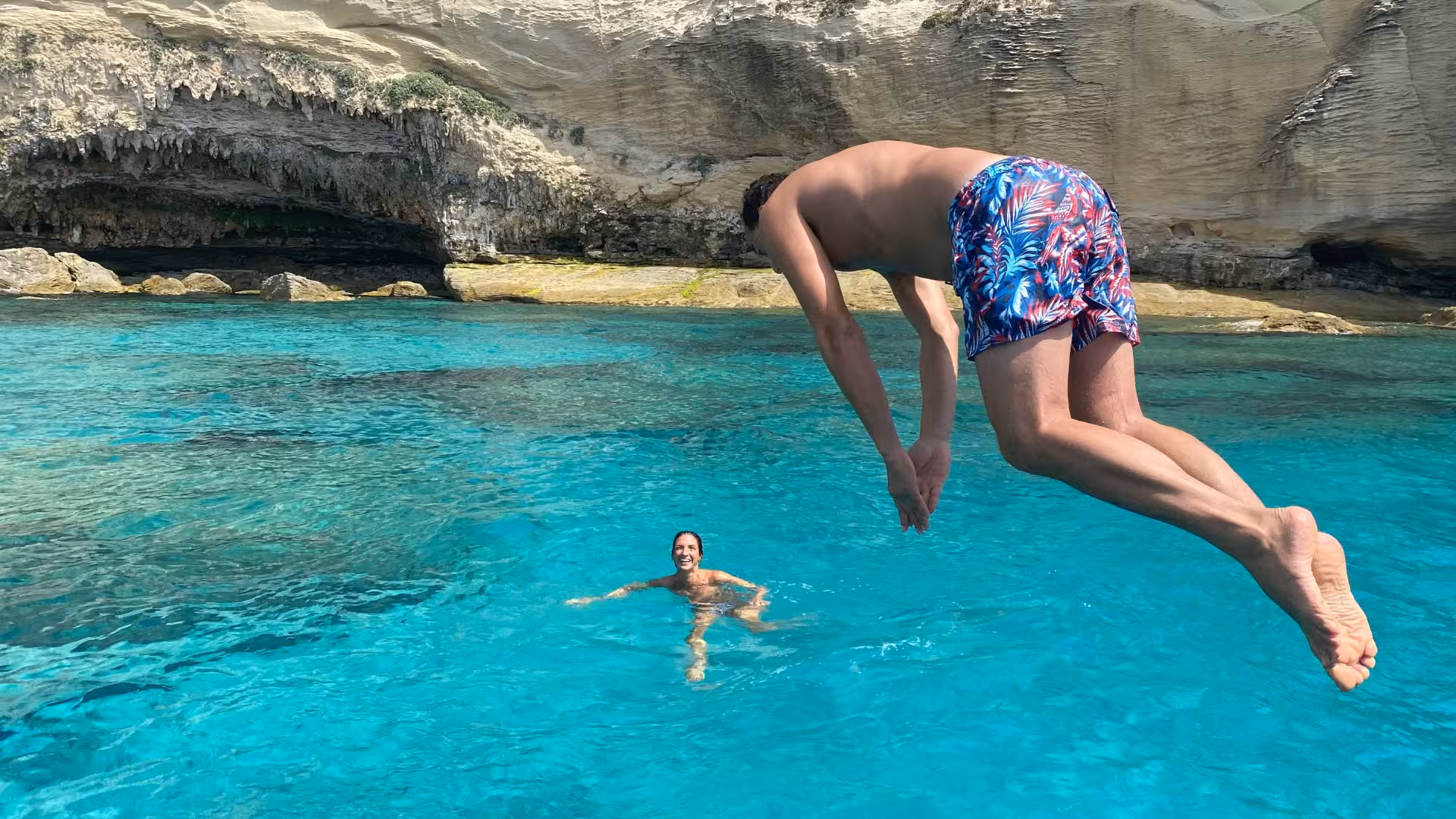 Man diving into crystal-clear waters near rocky cliffs in southern Corsica, perfect for adventurous RIB tours.