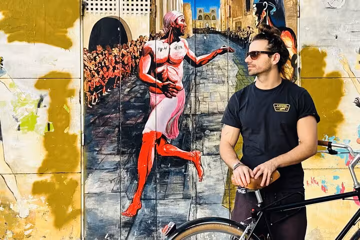 Man with Dutch-style omafiets city bike by colorful mural, ideal for easy city bike rental and sightseeing