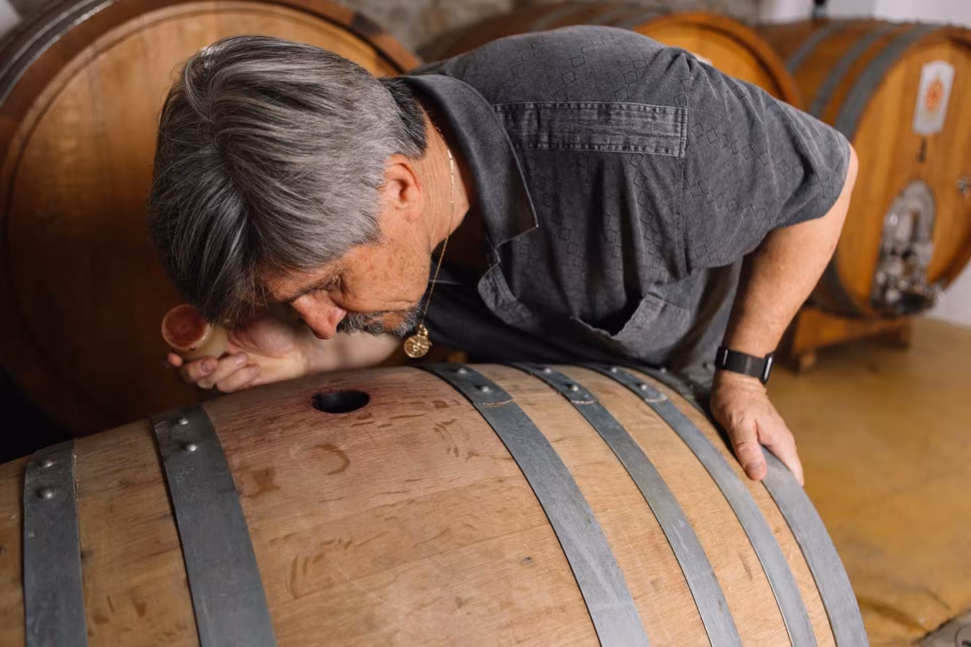 Man inspecting wine barrel in Gallura winery, highlighting authentic Sardinian wine-making process.