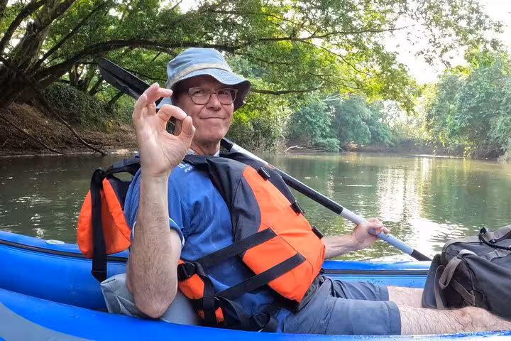 Man in a kayak on Río Celeste gives an OK sign, enjoying the calm and scenic surroundings of the tour.