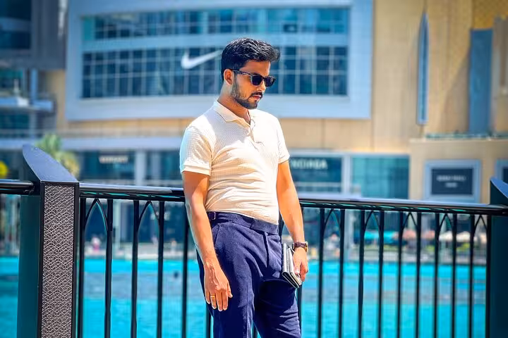 Man posing stylishly by Dubai Fountain during Burj Khalifa Instagram tour with a travel videographer.