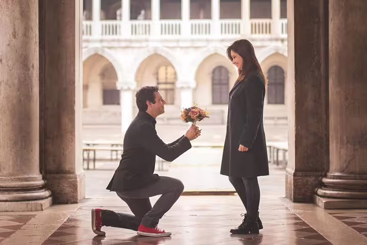 Man proposing with bouquet in Venice arcade during a city portrait session, classic architecture in background
