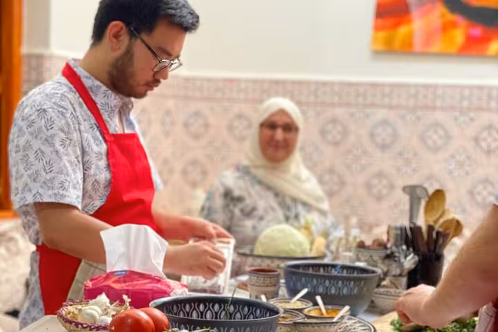 Man in a red apron preparing ingredients while participating in a hands-on family cooking class.