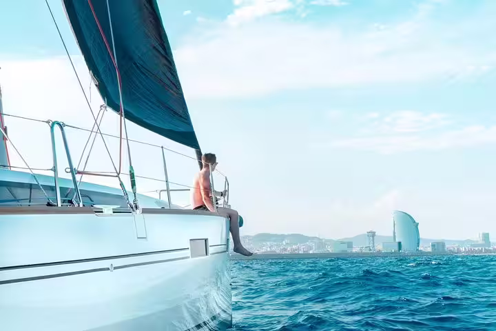 Man relaxing on a sailboat during a 2-hour small group cruise with food and drinks, overlooking Barcelona's scenic coastline.
