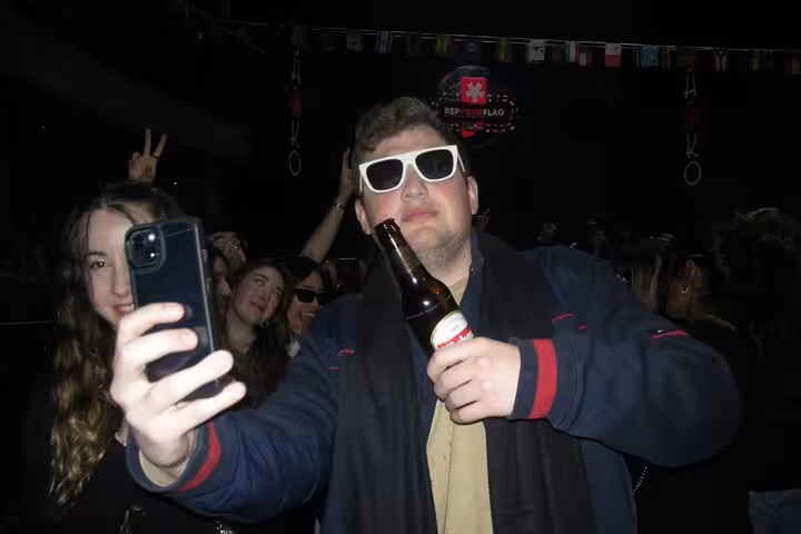 Man taking a selfie with sunglasses and a drink, capturing the lively atmosphere of Barcelona's nightlife.