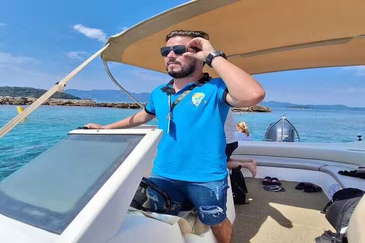 Man steering a boat in Angra and Ilha Grande tour, enjoying sunny skies and clear blue waters.