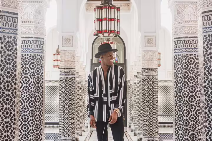 Man in stylish outfit and hat posing among ornate columns during a private photo shoot in Marrakesh, Egypt.