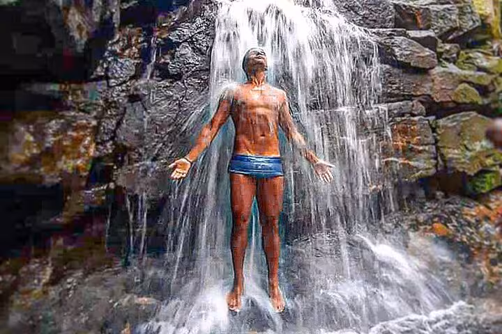 Man enjoying the refreshing waterfall at Pedra da Gávea, a highlight of the Garganta do Céu hiking adventure.