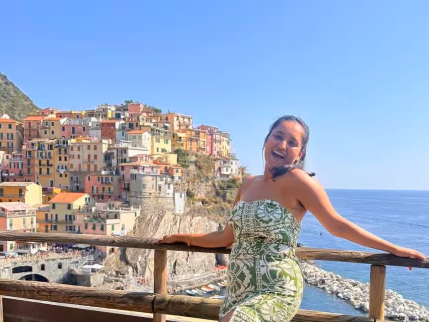 Visitor enjoying a sunny day on the terrace overlooking the colorful cliffside village of Manarola, Cinque Terre.