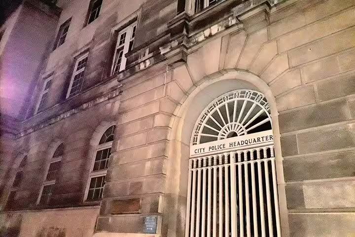 Historic Manchester City Police Headquarters building at night with ornate arched iron gate