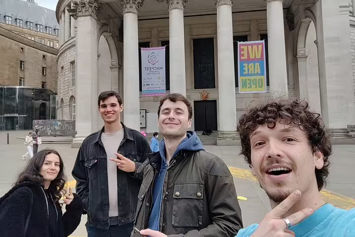 Group of four young people taking a selfie in front of a historic Manchester building with columns
