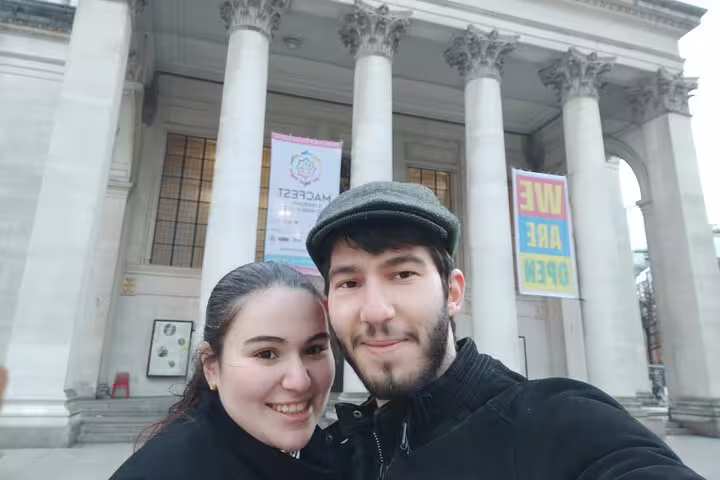 Couple smiling in front of Manchester museum with large classical columns and event banners