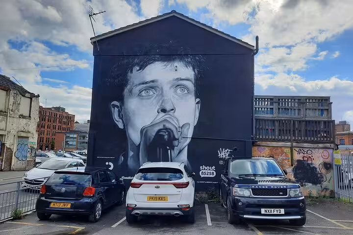 Large black and white street art mural of a singer with microphone on building wall in Manchester