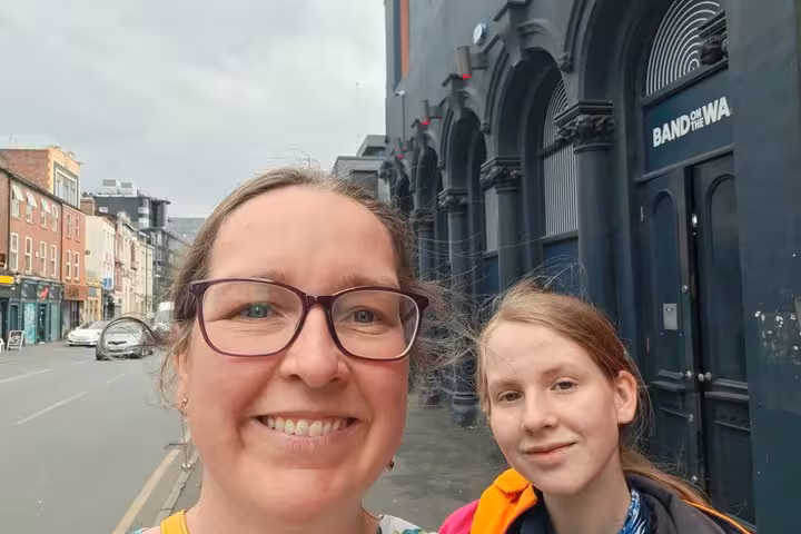 Two people smiling on a Manchester street outside Band on the Wall music venue