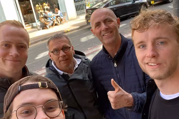 Group of four men smiling for a selfie on a city street