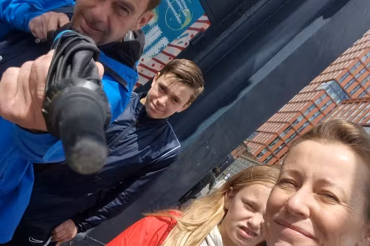 Group of four people taking a fun selfie outdoors near a brick building on a street tour