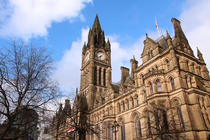 Manchester Town Hall clock tower on a blue-sky day, key stop on self-guided audio scavenger hunt tour