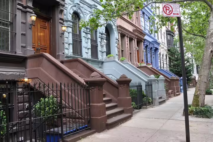 Colorful brownstone townhouses with stoops along a tree-lined sidewalk in Manhattan, New York City