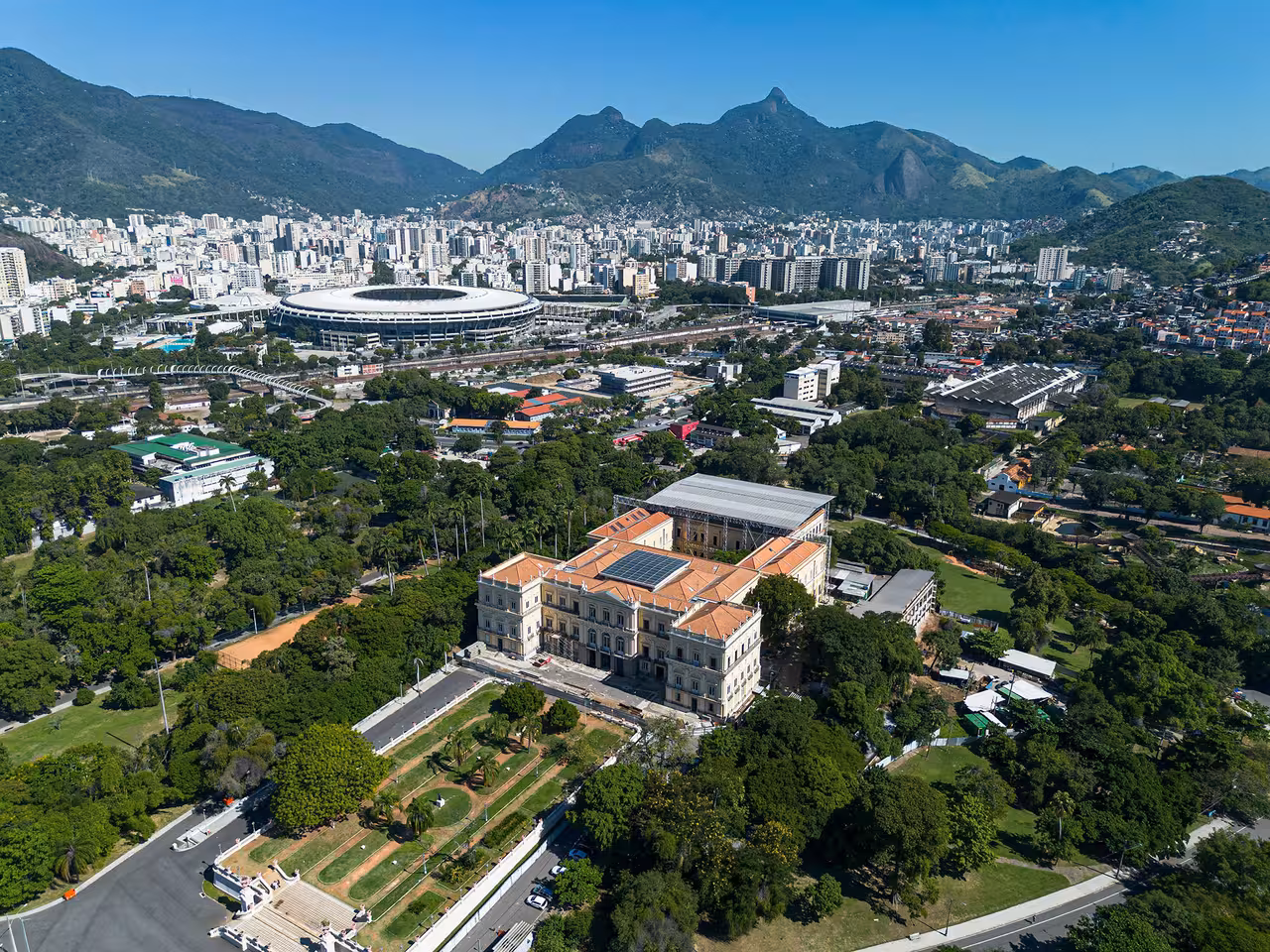 Aerial view of Maracanã Stadium in Rio de Janeiro surrounded by lush greenery and urban landscape, ideal for soccer match tours.